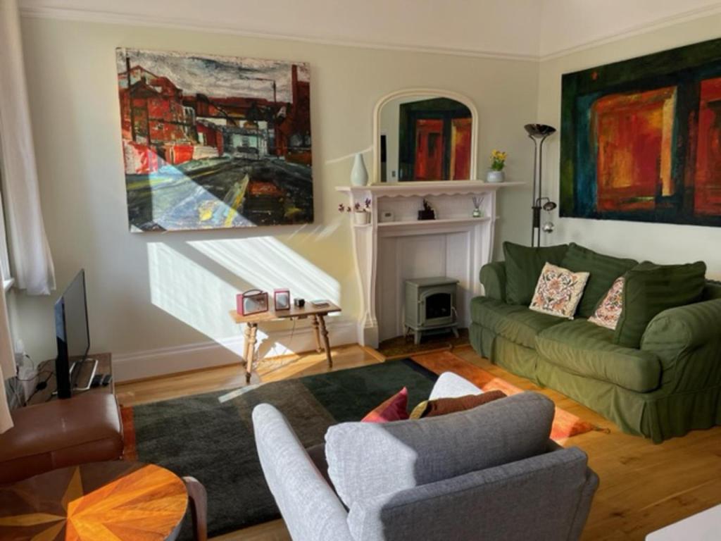 a living room with a green couch and a fireplace at Beautifully Lit Airy 1-Bed Apartment in Liverpool in Liverpool