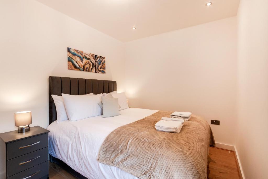 a bedroom with a bed with white sheets and a nightstand at Cozy Two Bedrooms Flat in Coulsdon, CR5 in Coulsdon