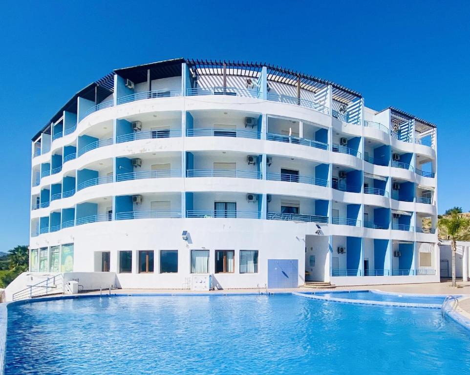 een groot wit gebouw met een zwembad ervoor bij Cabo Dream Apparthotel in Cabo Negro
