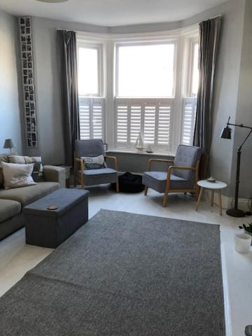 a living room with a couch and chairs and windows at Beach Flat Lytham St Annes in Lytham St Annes