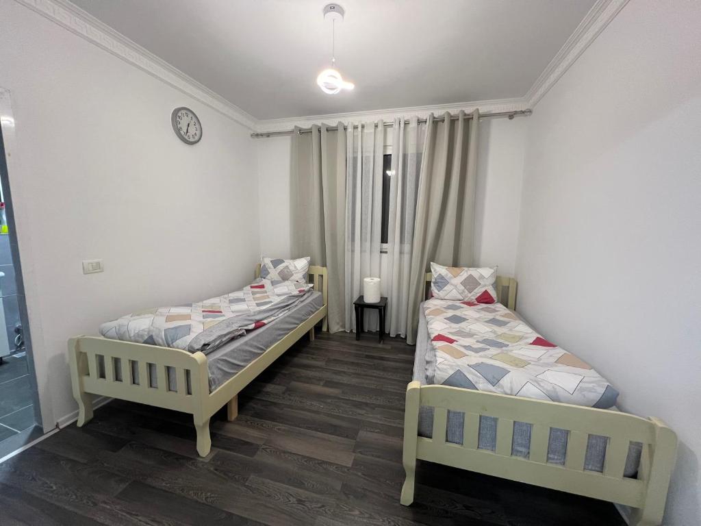 sypialnia z 2 łóżkami i zegarem na ścianie w obiekcie Canyon's house w mieście Çorovodë
