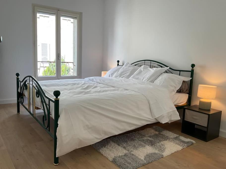 a bedroom with a bed with white sheets and a window at Duplex « Les pieds dans l’eau » in Nernier