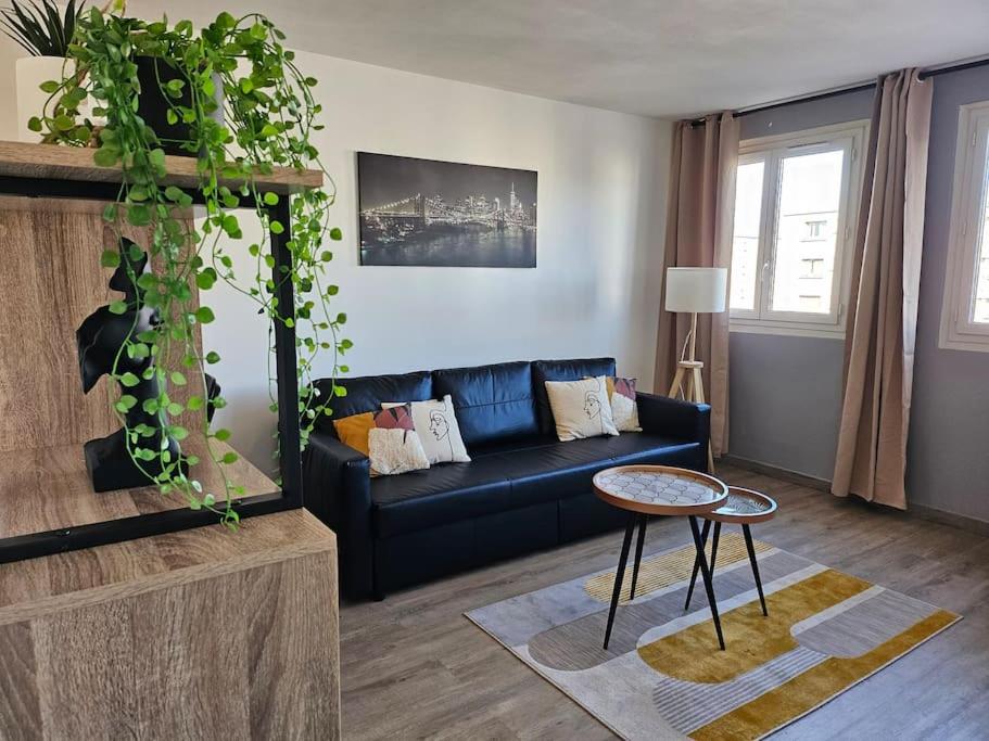 een woonkamer met een blauwe bank en een tafel bij Appartement Art deco proche bords de Marne in Neuilly-sur-Marne