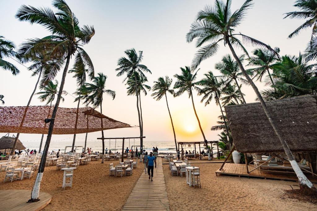 a man walking down a beach with palm trees at Thalassa Beach Boutique Resort in Goa Velha