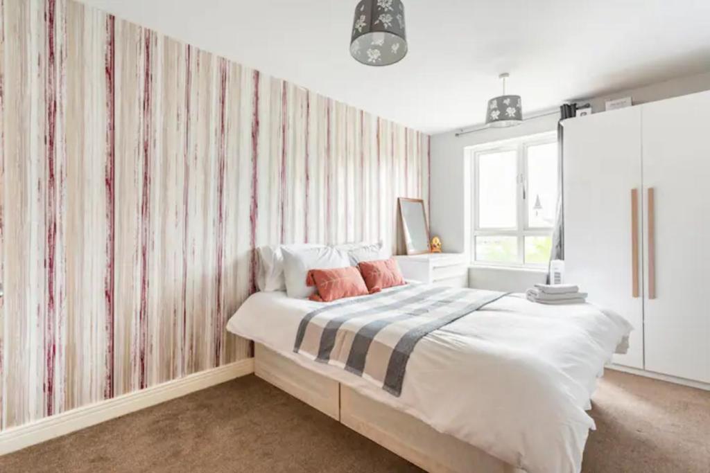 倫敦的住宿－Lovely en-suite double room，一间卧室配有一张带条纹壁纸的大床