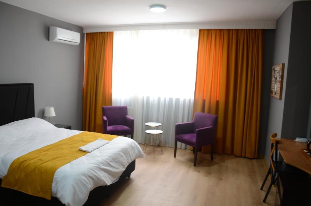 Habitación de hotel con 1 cama y 2 sillas moradas en BY KARAM SUİT, en Estambul