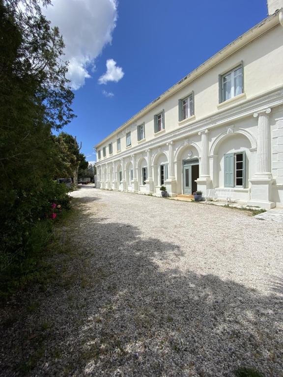 a large white building with a gravel driveway at HOTEL LE FLOREAL in Le Soler