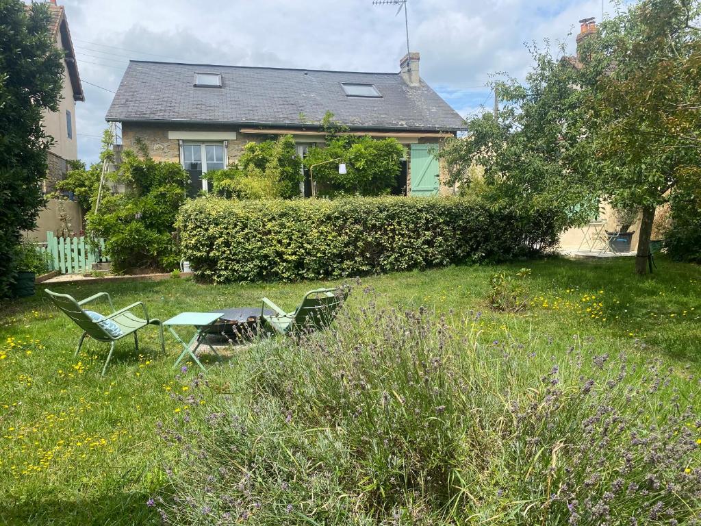 une cour avec deux chaises et une table en face d'une maison dans l'établissement Cottage familial avec jardin à Dives-sur-Mer, à Dives-sur-Mer