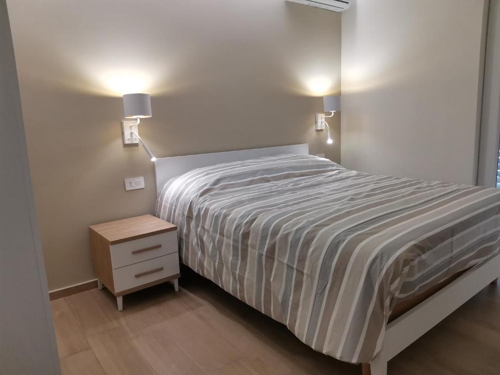 een slaapkamer met een bed en een nachtkastje met 2 verlichting bij Palazzo Buscema - Casa & Vacanza in Crotone