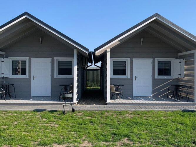 a building with white doors and a porch with tables at Comfortable holiday homes in Dziwnówek in Dziwnówek