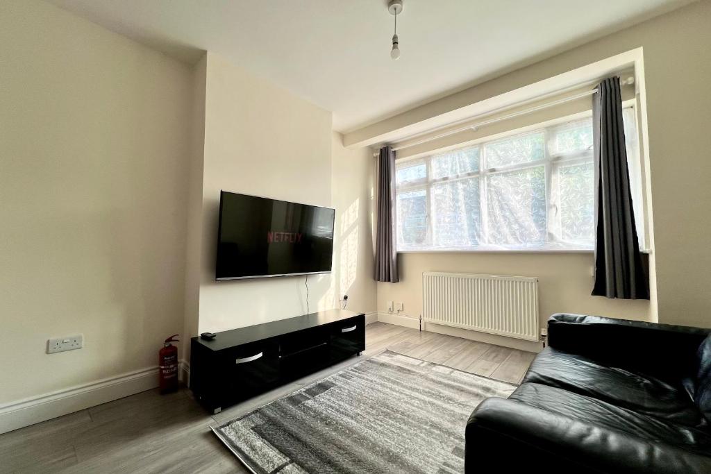 a living room with a couch and a flat screen tv at 3 Bedroom Holiday Home in Hackbridge