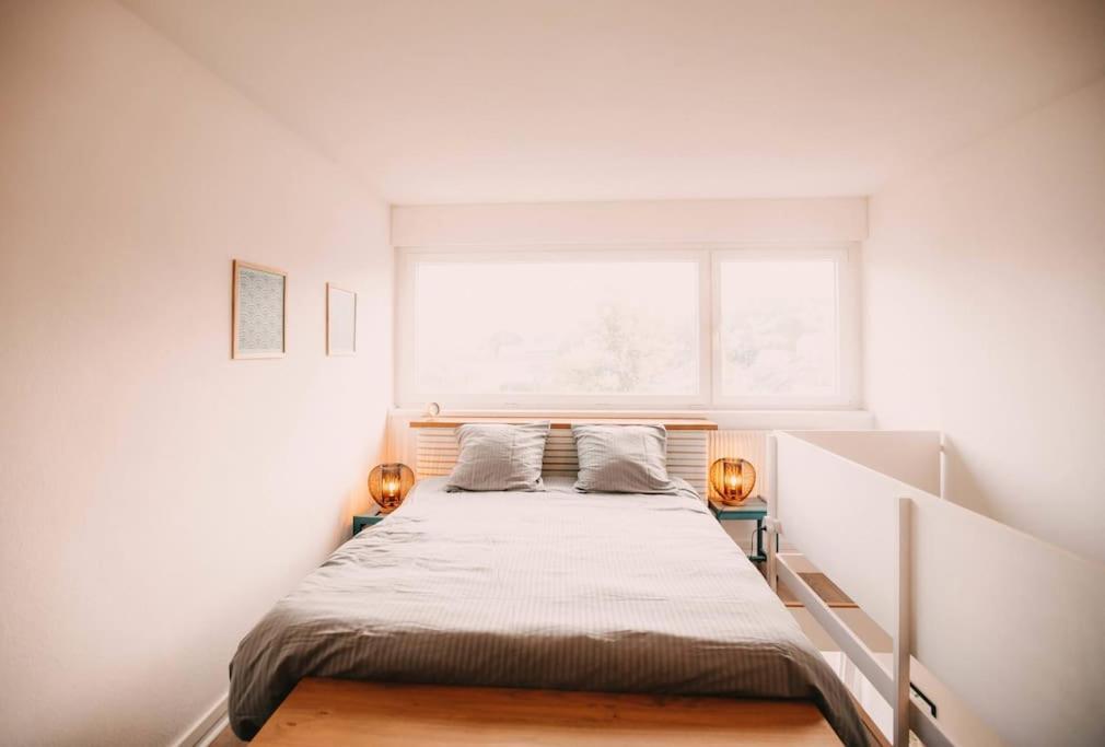 een bed in een witte kamer met een raam bij Soirée cinéma quartier Mouillère in Besançon