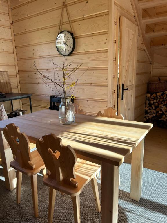 une table et des chaises en bois dans une chambre avec une horloge dans l'établissement Babiogórskie klimaty, à Zawoja