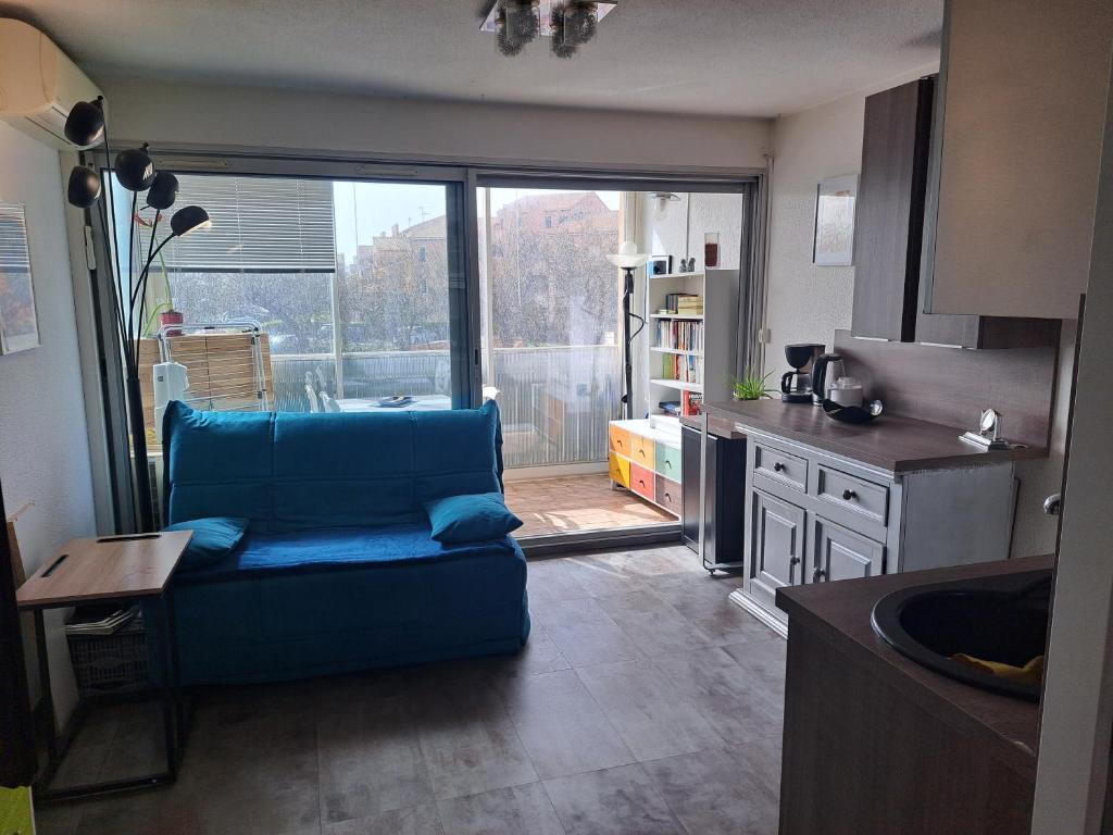 eine Küche mit blauem Sofa in der Mitte eines Zimmers in der Unterkunft Appartement T2 à 300m de la mer in Palavas-les-Flots