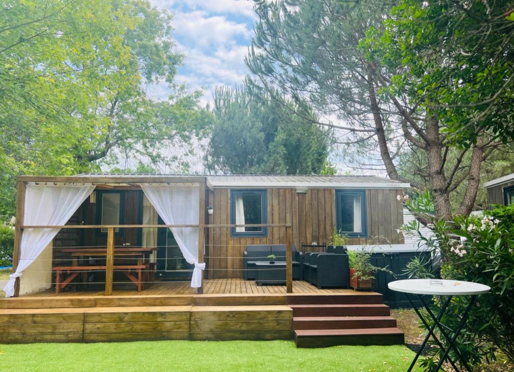 une petite maison avec une terrasse dans une cour dans l'établissement Camping MAYOTTE TOHAPI 5 étoiles, à Biscarrosse