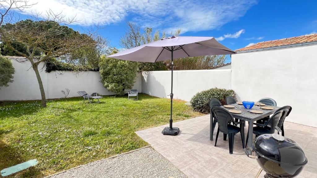 une terrasse avec une table et un parasol dans l'établissement Jolie maison à étage avec jardin et parking privé, au Bois-Plage-en-Ré