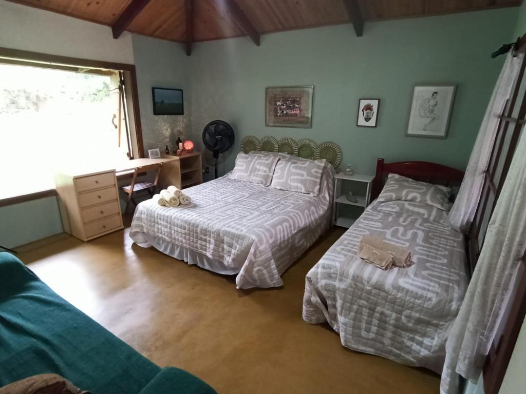 a bedroom with two beds and a desk and a window at Chalés Pássaros do Cerrado in Cavalcante