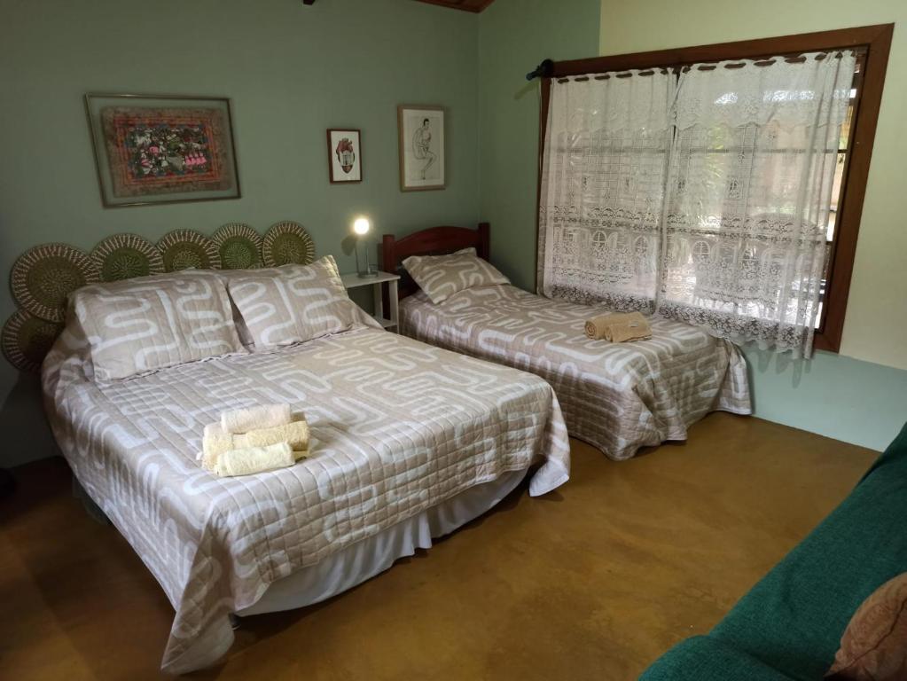 a bedroom with two beds and a window at Chalés Pássaros do Cerrado in Cavalcante