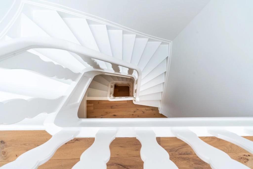 eine Treppe in einem Zimmer mit weißen Wänden und Holzböden in der Unterkunft B&B The Four in Mechelen