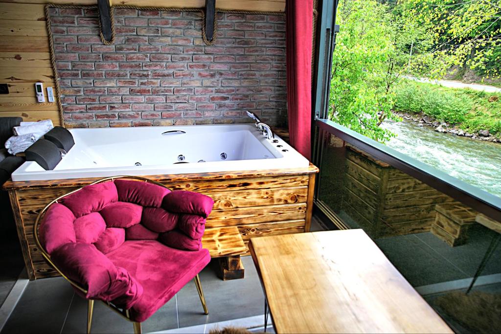 a red chair sitting in front of a bath tub at Tabiat Bungalows in Çamlıhemşin