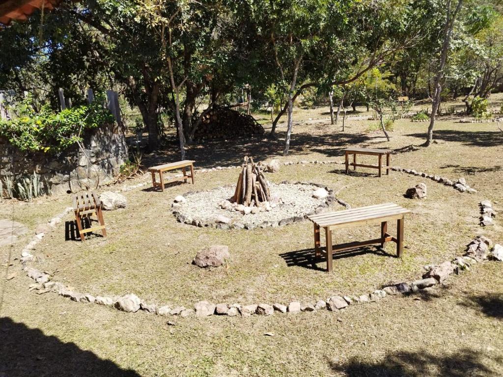 a park with two benches and a fire pit at Chalés Pássaros do Cerrado in Cavalcante