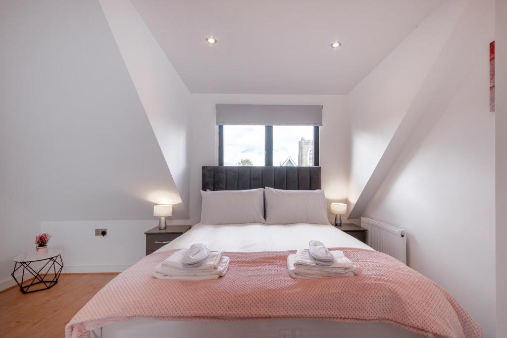a white bedroom with a large bed with towels on it at Cozy Studio Flat in Coulsdon, CR5 in Coulsdon