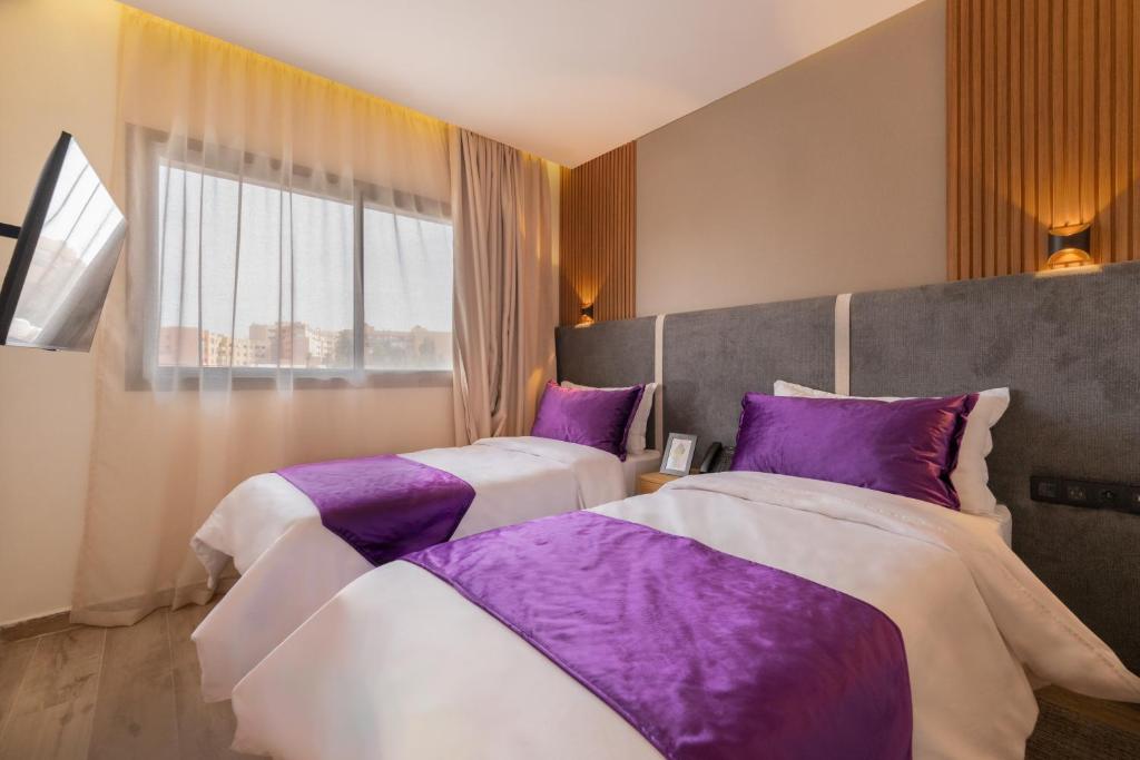 2 Betten in einem Zimmer mit lila Kissen in der Unterkunft Appart Hôtel Rambla in Marrakesch