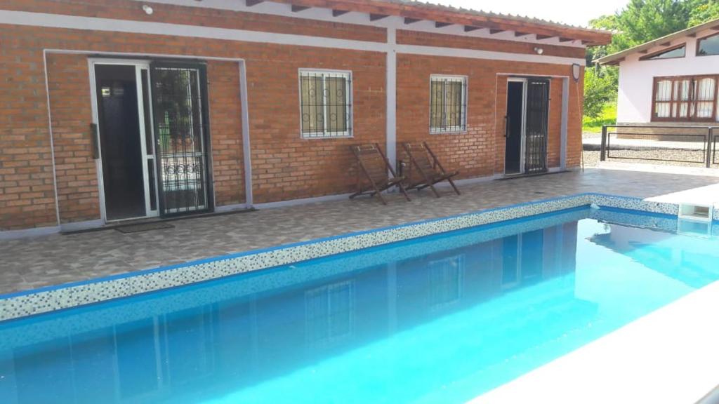 a swimming pool in front of a brick house at LAPACHO II in Puerto Leoni