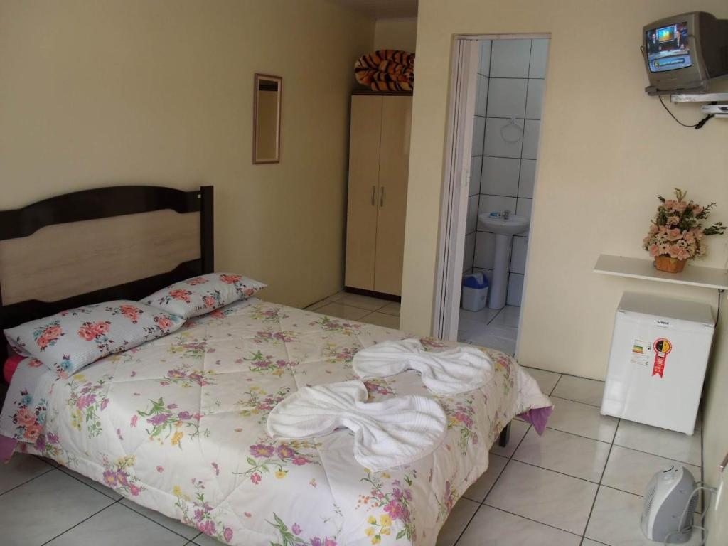 um quarto com uma cama com um edredão branco em Pousada da Mari em Gramado