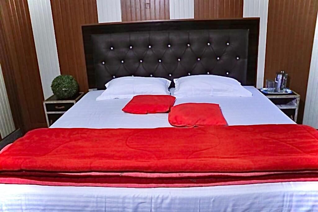 a large bed with red sheets and white pillows at Flagship Corbett Farm Homestay in Rāmnagar