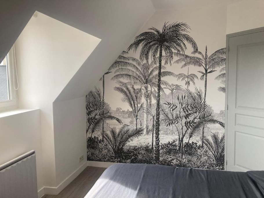 a bedroom with a palm tree mural on the wall at Appartement cosy Pleine Fougères in Pleine-Fougères