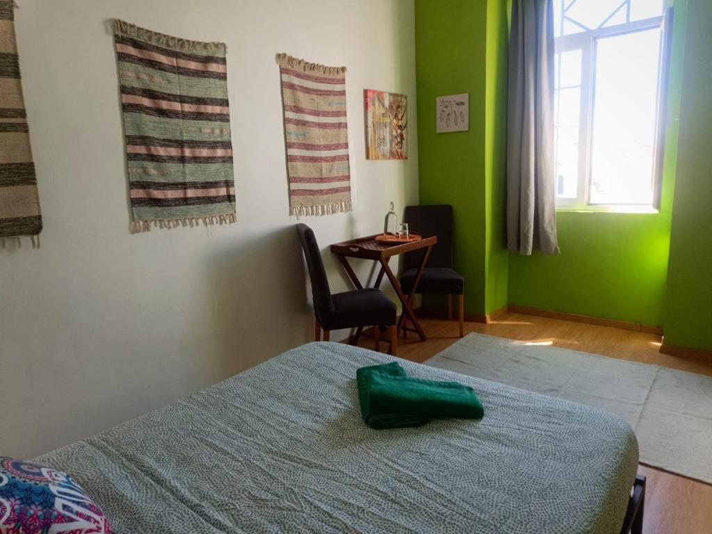 1 dormitorio con paredes verdes, 1 cama y 1 mesa en Meraki Hostel, en Sintra