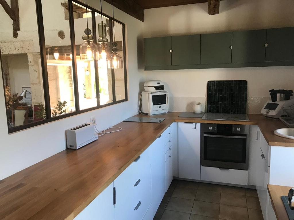 a kitchen with white cabinets and a wooden counter top at Maison piscine Lot in Laburgade
