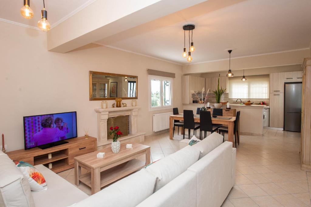 a living room with a white couch and a tv at John & Angelo Villa in Akrotiri