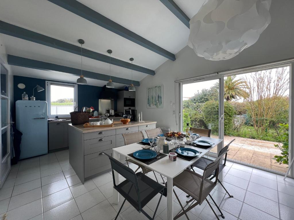 a kitchen with a white table and chairs and a kitchen with blue walls at Villa de la Cible in Saint-Martin-de-Ré
