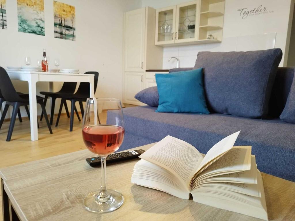 a glass of wine and a book on a coffee table at Ferienzimmer Reinisch in Tattendorf in Tattendorf