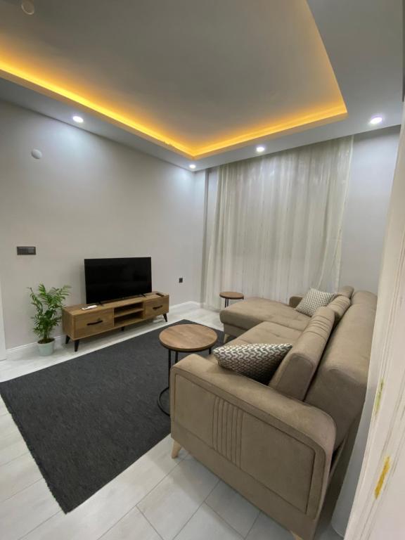 ein Wohnzimmer mit einem Sofa und einem Flachbild-TV in der Unterkunft Antalya Havalimanına Yakın Havuzlu 1+1 Lux Daire in Antalya