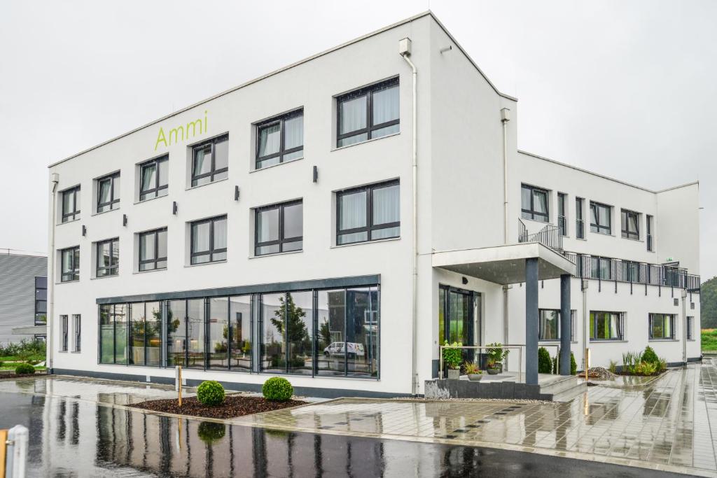 ein weißes Gebäude im Regen mit Wasser auf der Straße in der Unterkunft Ammi Hotel Garni in Inning am Ammersee