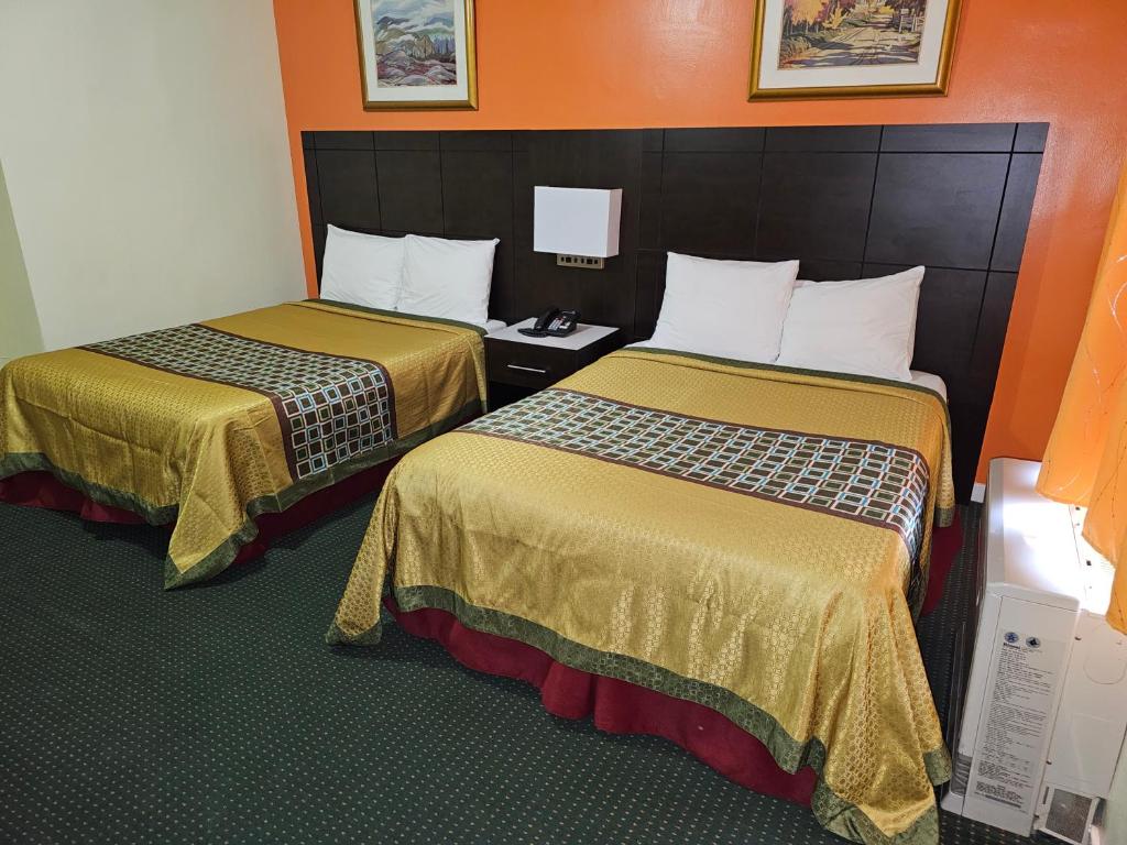 duas camas num quarto de hotel com paredes cor de laranja em Norvic Motel em Coniston