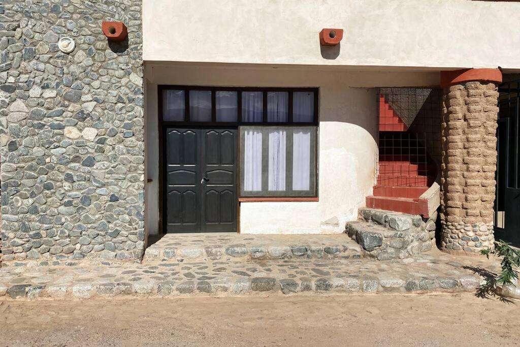 una casa in pietra con porta nera e scale di PACHA PUNKU en San Carlos a San Carlos