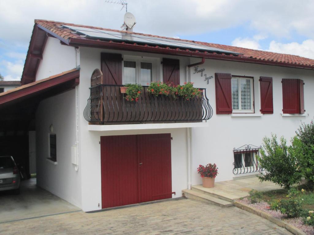 a white house with a red door and a balcony at Studio entre montagne et mer in Cambo-les-Bains