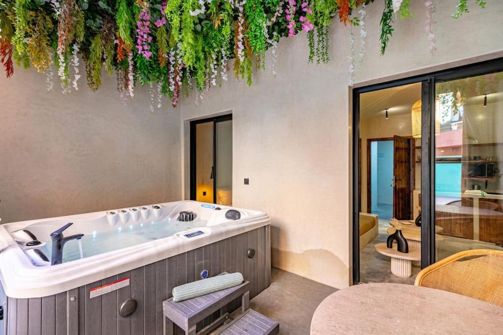 a bathroom with a tub with flowers hanging from the ceiling at Suite de luxe + jacuzzi à Gueliz in Marrakech