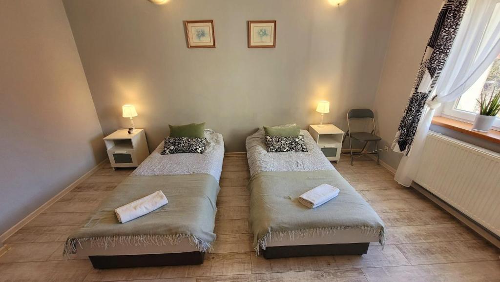 dwa łóżka w pokoju z dwoma stołami i oknem w obiekcie Apartament "Przy Jeziorku" w mieście Kętrzyn
