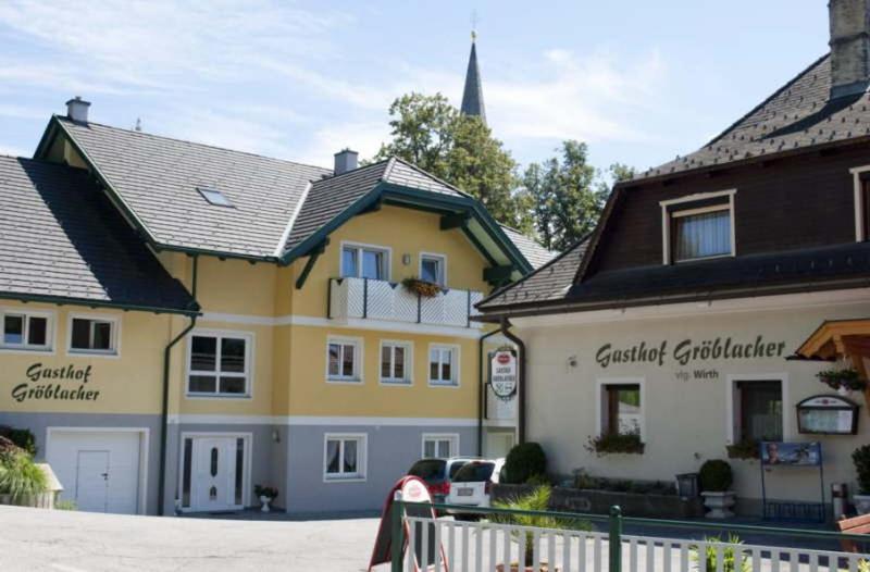 Gästehaus Gröblacher في Köstenberg: مبنى اصفر وبيض مع كنيسه