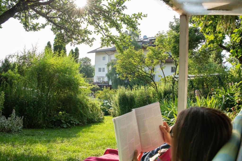 a woman reading a book in the garden at Hotel Heubad in Völs am Schlern