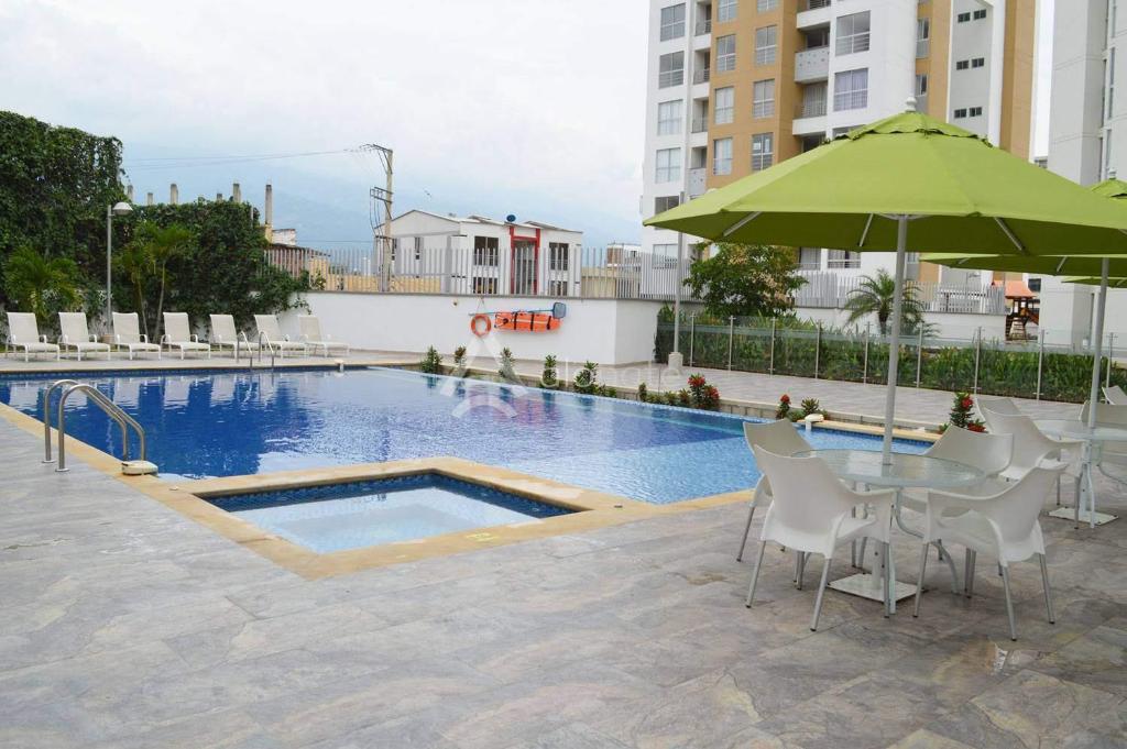 - une piscine avec une table et un parasol vert dans l'établissement Gaira Apartamento Amoblado Bucaramanga, à San Gil