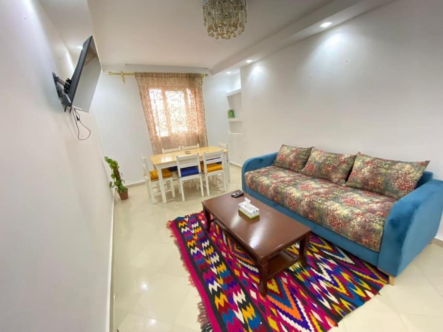 ein Wohnzimmer mit einem blauen Sofa und einem Tisch in der Unterkunft Spacious Cozy Appartment Akid Lotfi ORAN in Oran