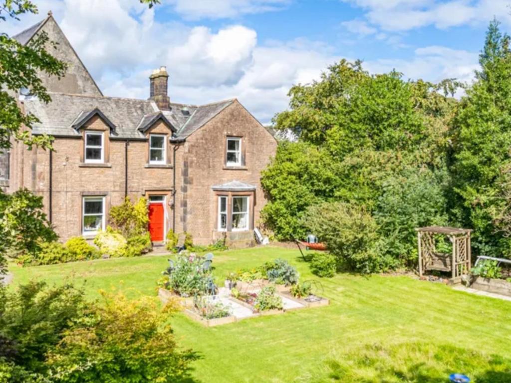 uma vista para o exterior de uma grande casa de tijolos com um jardim em Mansefield Rooms em Lockerbie