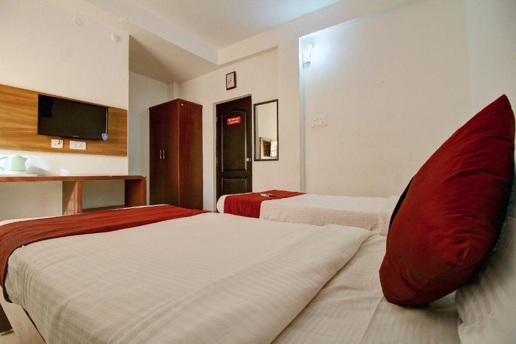 een hotelkamer met 2 bedden met rode kussens bij OYO The Mangrove Wood Residency in Chennai