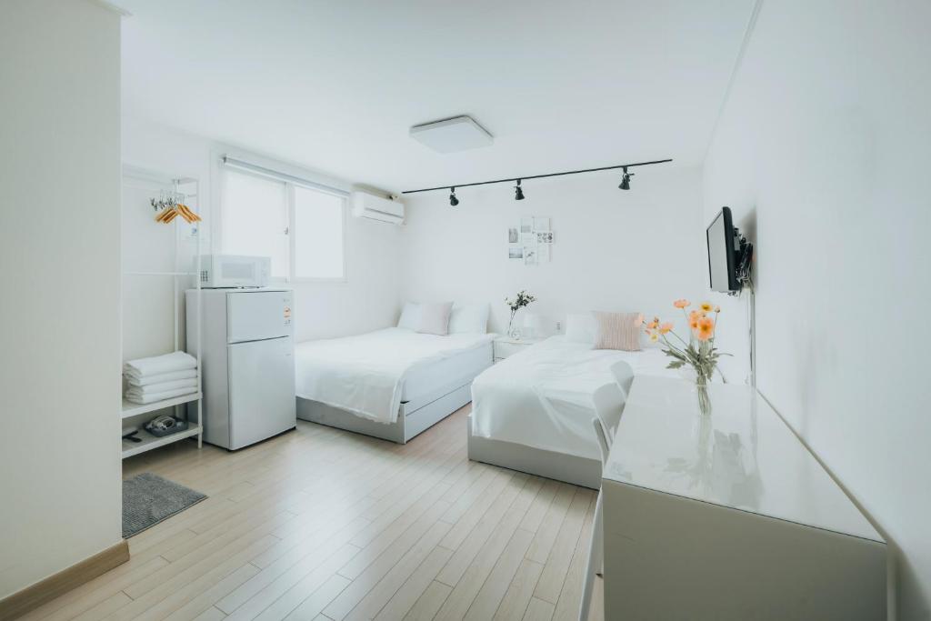 Cette chambre blanche comprend deux lits et un réfrigérateur. dans l'établissement DK House, à Séoul